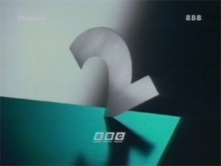 A silver '2' has fallen into a green surface, point-side first, casting a shadow in front of it (17K)