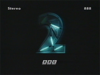 Six flourescent light tubes are arranged in a '2'-shaped tray, some are lit, illuminating the tray, which is surrounded by darkness (11K)